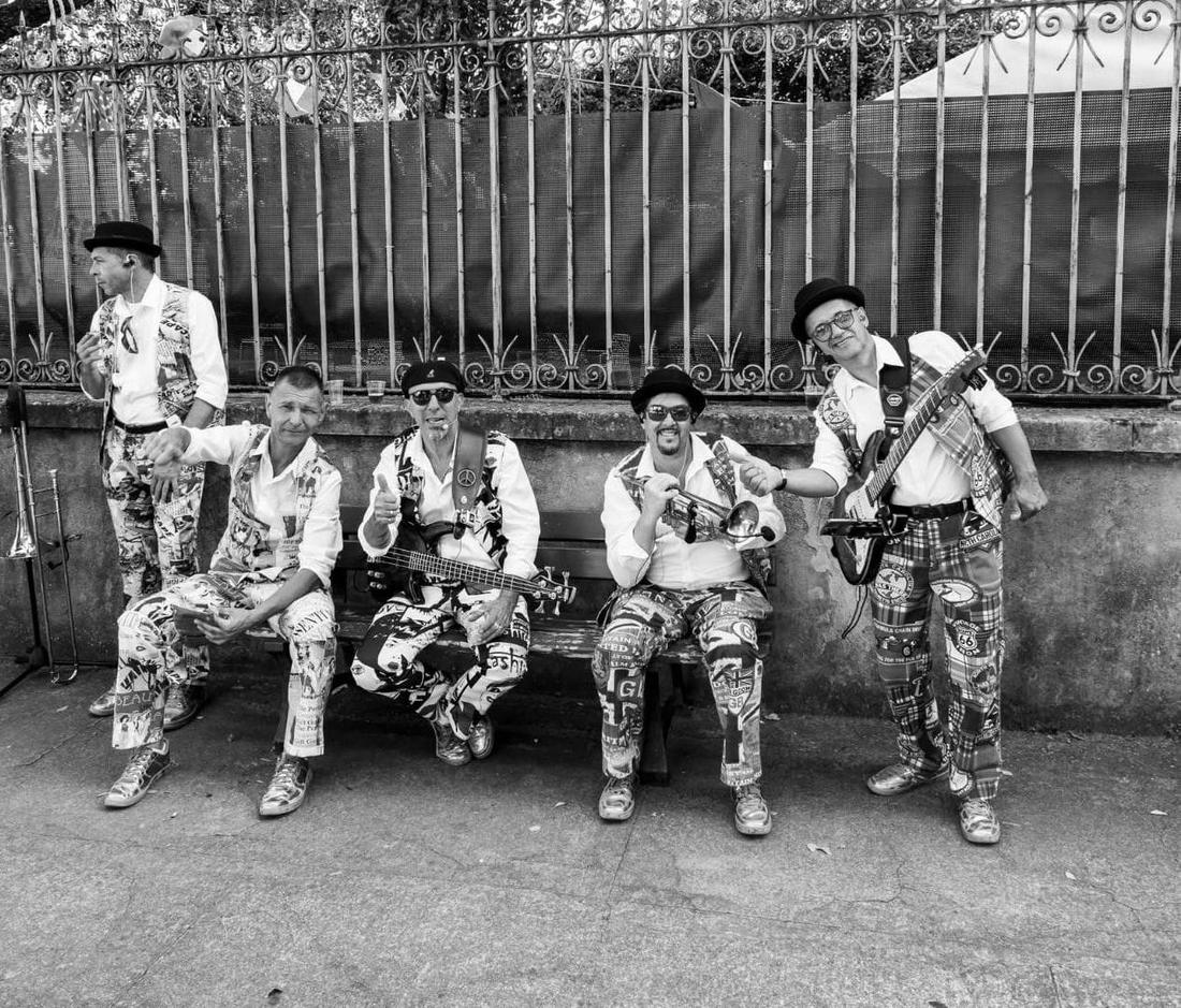 Les cinq musiciens de Street Shakers en pause sur un banc, instruments à la main, photo noir et blanc