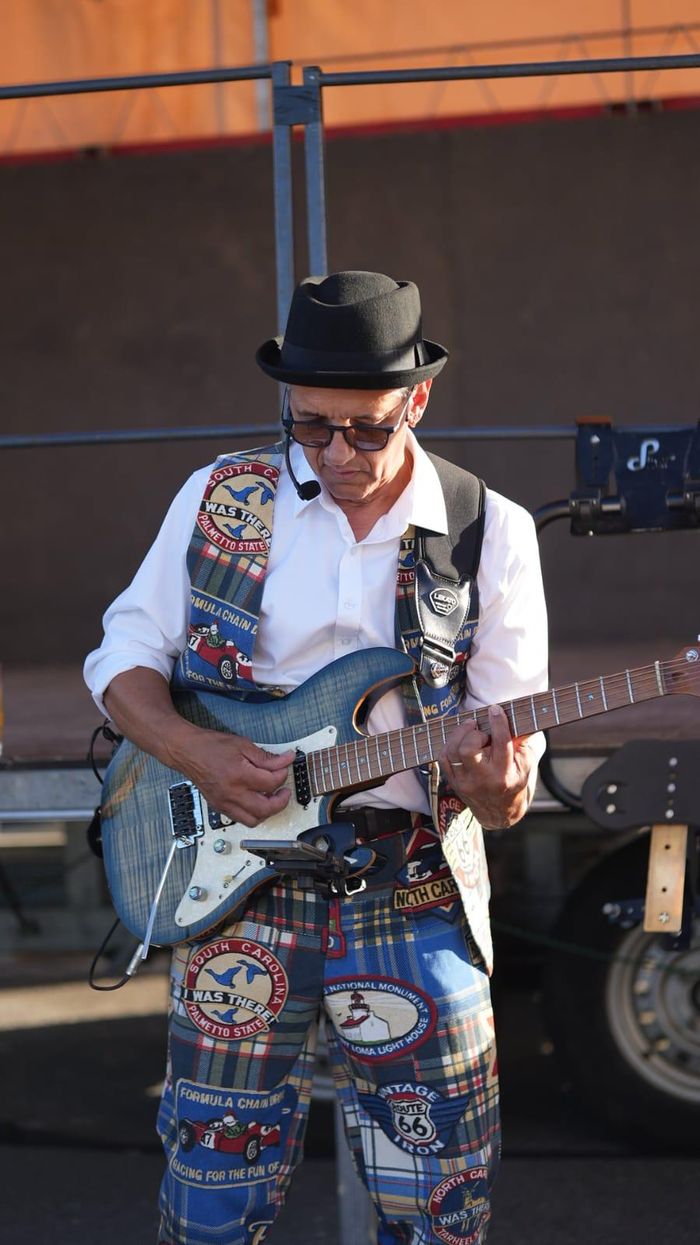 Michel à la guitare électrique, pantalon écossais à écussons